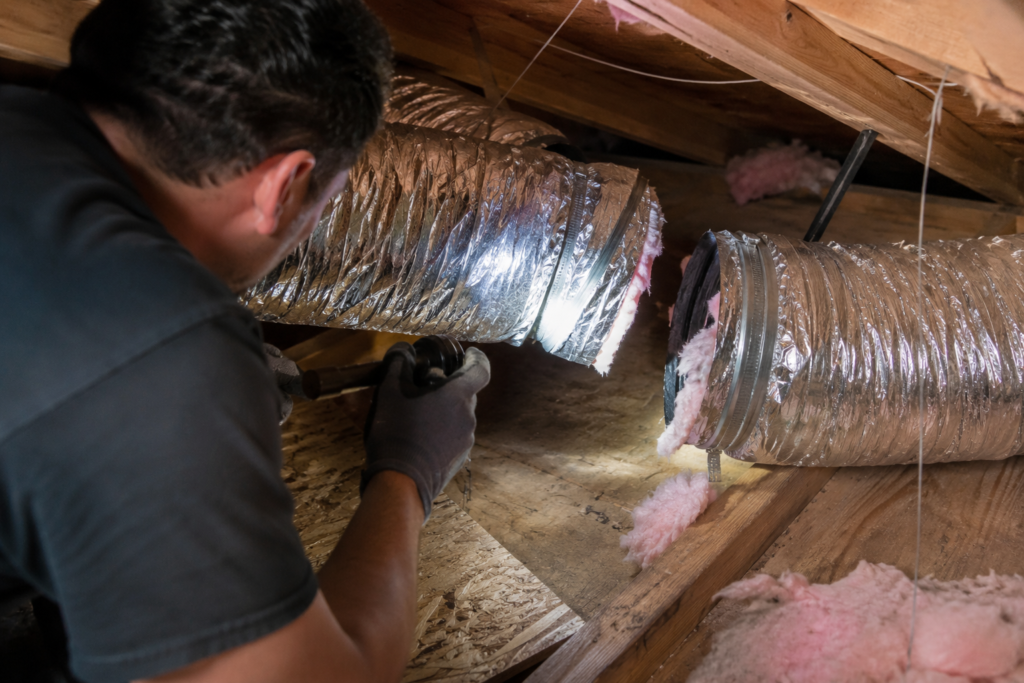 HVAC technician inspecting a disconnected duct joint in a San Francisco home's attic during the rainy season